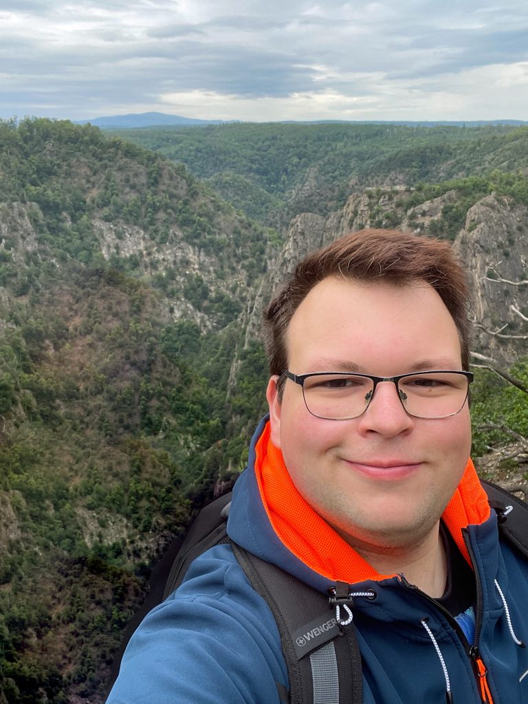 Mika Krämer an einem Berghang mit Wolken im Himmel. Mediengestalter und Webdesigner Naminex